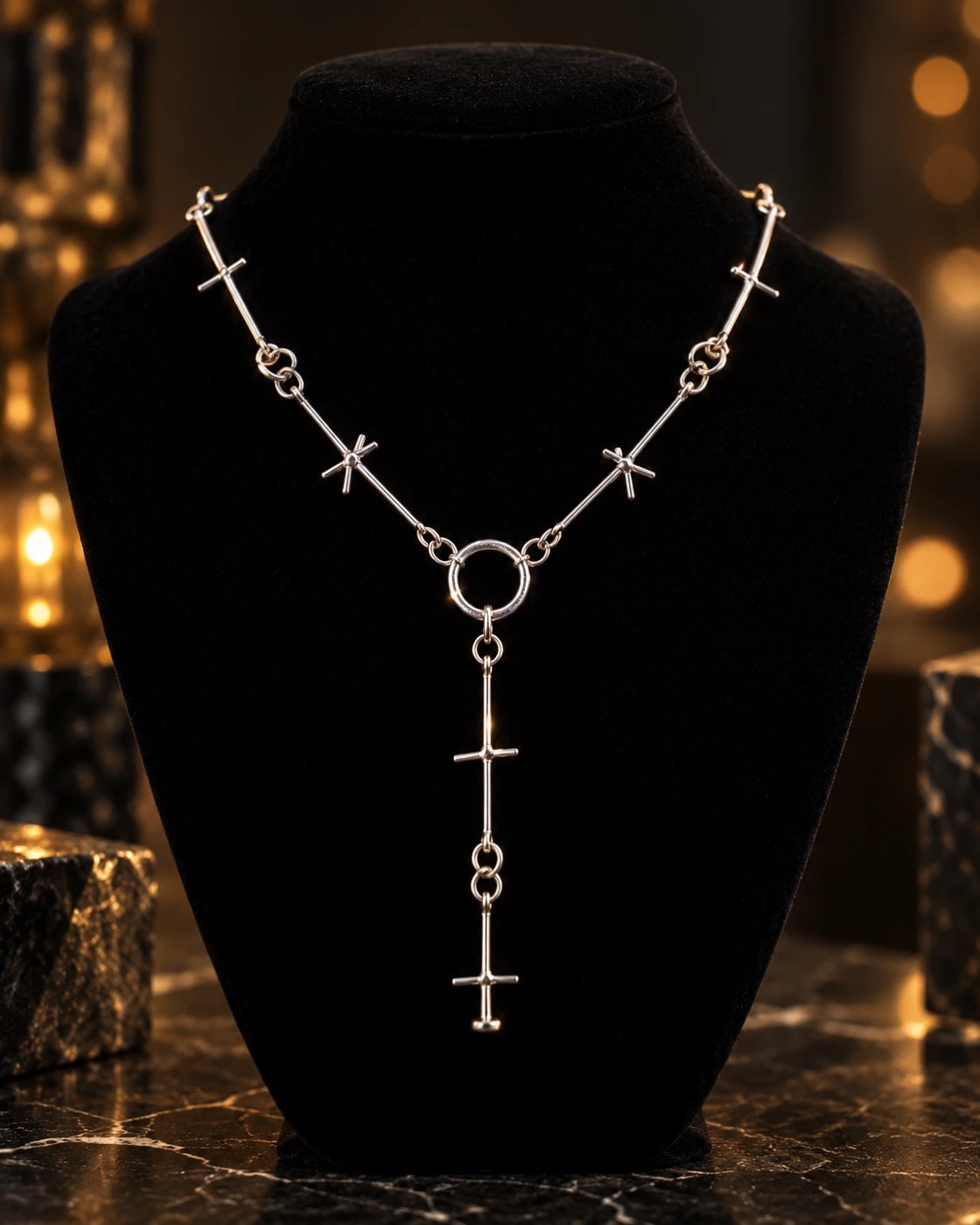 Silver lariat necklace of cross-shaped bar links passing through a central ring, with a cross pendant drop, on a black velvet bust